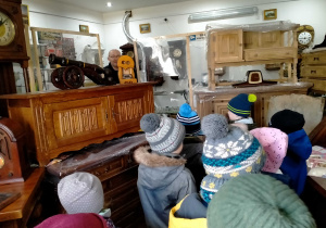 Dzieci słuchają o zawodzie zegarmistrza i historii zegarów wahadłowych.