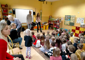 Dzieci siedzą na dywanie i słuchają piosenki śpiewanej przez p.Sylwię i p. Agnieszkę.
