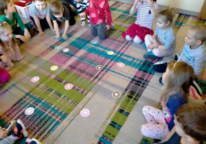 Dzieci oglądają sylwety pączków, porozkładane na dywanie.