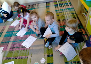 Dzieci słuchają jak mają wykonać "pączkowe" Karty Pracy.