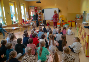 Dzieci siedza na dywanie i słuchają piosenki śpiewanej przez p.Ulę i p. Agnieszkę.