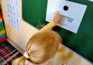 Dziewczynka przyczepia fragment klucza na planszy.