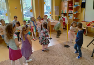 Dzieci przechodzą pod kijkiem "Limbo" umieszczonym miedzy pachołkami.