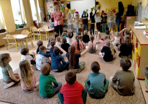 Kilkoro dzieci tańczy z p.Ulą, reszta siedzi na dywanie.