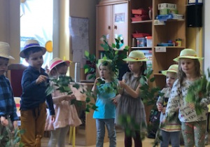 Dzieci stoją i machają liśćmi w rytm muzyki.
