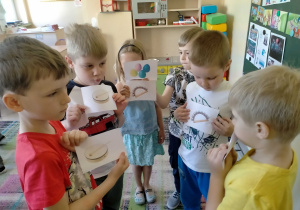 Dzieci tworzą koła tematyczne z wymienionymi przez nauczyciela instrumentami na obrazkach.