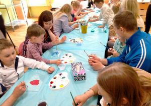 Dzieci z rodzicami malują na szkle.