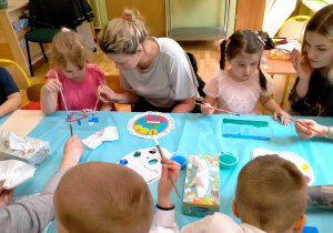 Dzieci z rodzicami malują na szkle.