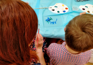 Chłopiec z mama malują kotka na szkle.
