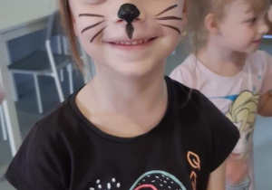 Dziewczynka z pomalowaną twarzą kotka.