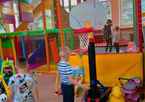 Chłopiec gra w koszykówkę kolorowymi kulkami.