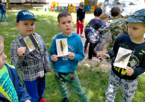 Dzieci prezentują obrazki z okazów naturalnych umieszczonych na kartce.
