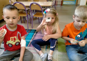 Dziewczynka i chłopcy prezentują wykonane własnoręcznie "marakasy".