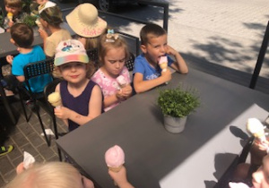 Dzieci siedzą przy stoliku z lodami.