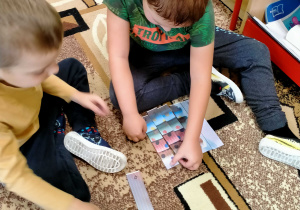 Chłopcy układają puzzle z obrazkiem kredy w kropki.