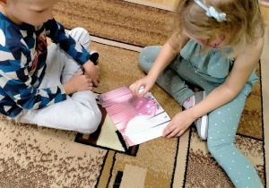 Dziewczynka z chłopcem układają puzzle z obrazkiem balonów w kropki.