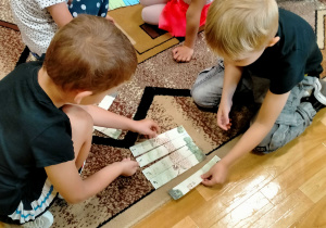 Chłopcy układają puzzle z obrazkiem geparda.