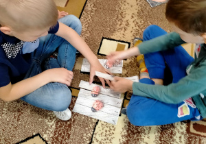 Chłopcy układają puzzle z obrazkiem biedronek.