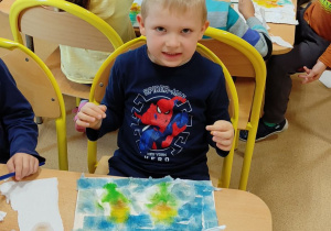 Chłopiec maluje słoneczniki.