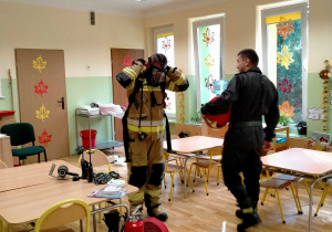 Strażak ubiera się w strój wykorzystywany podczas akcji pożarniczej.