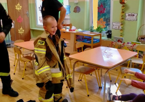 Chłopiec w stroju strażackim wykorzystywanym podczas akcji pożarniczej.