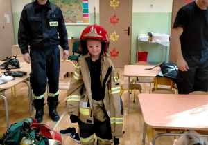 Chłopiec w stroju strażackim wykorzystywanym podczas akcji pożarniczej.
