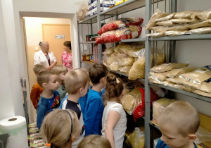 Dzieci oglądają produkty spożywcze zgromadzone w przedszkolnej spiżarni.