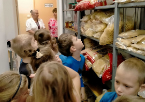 Dzieci oglądają produkty spożywcze zgromadzone w przedszkolnej spiżarni.