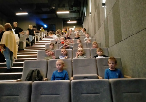 Dzieci siedzą w sali kinowej.