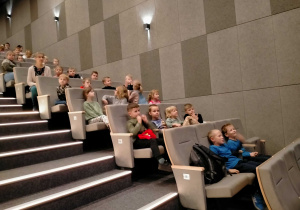 Dzieci siedzą w sali kinowej.