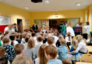 Dzieci śpiewają piosenki do akompaniamentu skrzypiec.