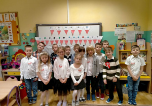 Dzieci stoją przy dekoracji z okazji "Święta Niepodległości".