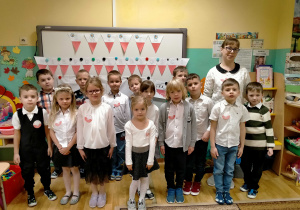 Dzieci stoją z p. Martą przy dekoracji z okazji "Święta Niepodległości".