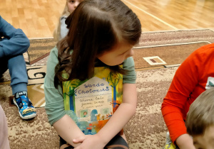 Dziewczynka trzyma na kolanach książkę Wandy Chotomskiej.