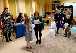 Dziewczynka otrzymuje nagrody i dyplom za piękny występ.