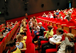 Dzieci siedzą na teatralnej widowni.