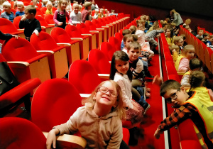Dzieci siedzą na teatralnej widowni.