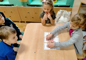 Dzieci układają puzzle z misiem.