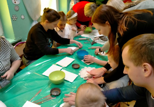 Dzieci wałkują serwetki na masie porcelanowej, aby uzyskać na niej wzory.
