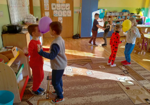 Dzieci tańczą w parach z balonami między czołami.