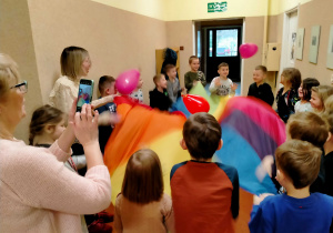 Dzieci bawią się chustą animacyjną i balonami w kształcie serc.