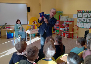 Pisarz pokazuje dzieciom swoja książkę pt. : "Czarownica Zołza".