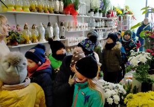 Pani florystka opowiada dzieciom o wiosennych kwiatach,, wykorzystywanych w okolicznościowych bukietach.