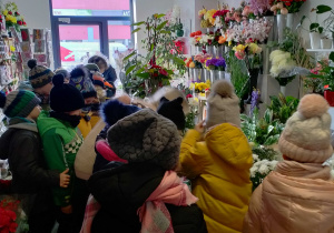 Dzieci oglądają różnorodne kwiaty w kwiaciarni.