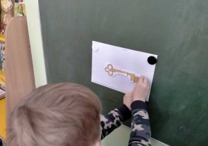 Chłopiec przykleja 5 część klucza na jego sylwetę.