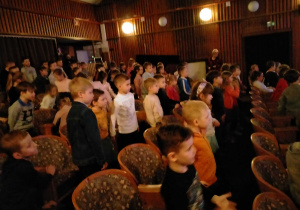 Dzieci stoją na widowni w teatrze.
