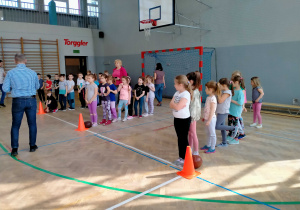 Dzieci stoją w rzędach, aby wykonywać zadania sportowe w drużynach.