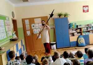 Pan z Muzeum, prezentuje dzieciom broń wykorzystywaną przez średniowiecznego rycerza..