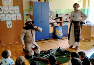 Pan z Muzeum, prezentuje dzieciom ubiór średniowiecznego rycerza.
