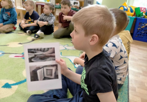 Dzieci oglądają zdjęcia, przedstawiające powstawanie glinianych przedmiotów.